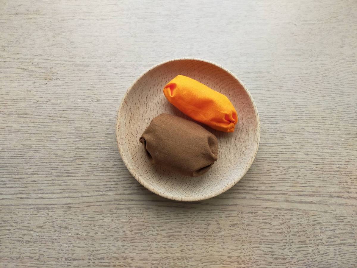 おままごとの具材。布で作ったお手玉がおままごと用のお皿に乗っている。見立て遊びで使う。