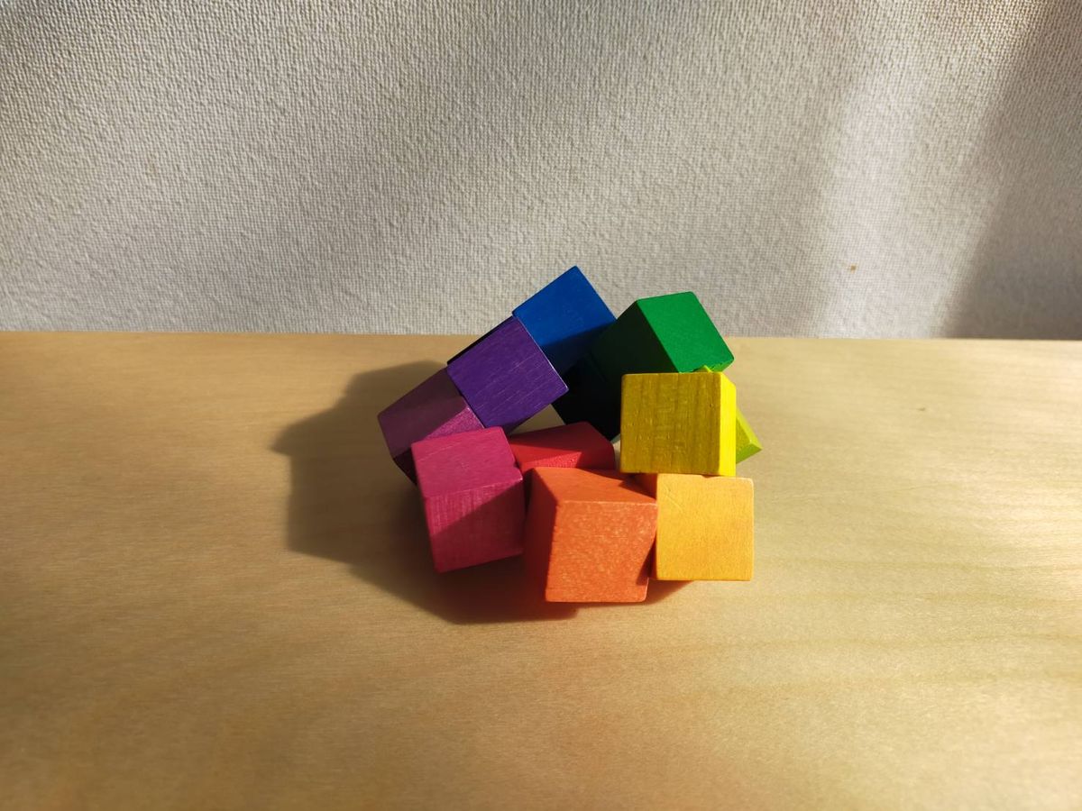 木製の色付きキューブパズルをばらばらに置いた写真
